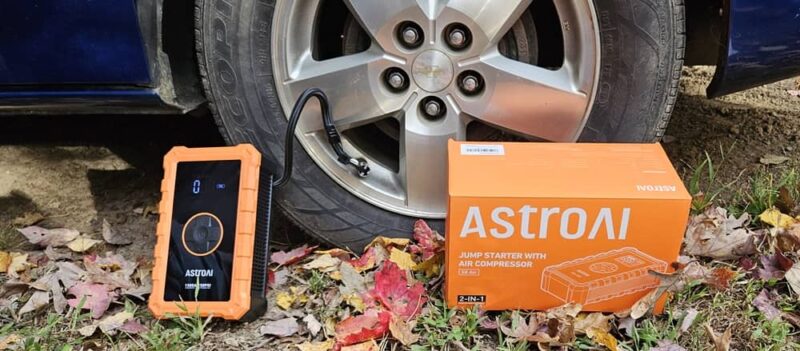 AstroAI S8 Jump Starter and box next to tire.