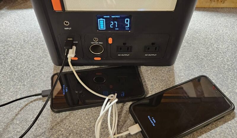 Two phones charging on the CYBPULTE C601 Portable Power Station.